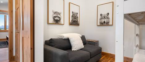 Una sala de estar moderna con un sofá gris, una manta blanca y láminas enmarcadas de animales en la pared.
