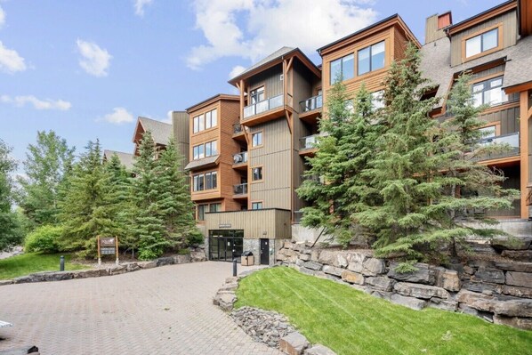A multi-story hotel with a stone facade, balconies, and a paved entrance area.