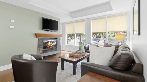 Una sala de estar con chimenea, sofá, televisor y ventana con vistas al exterior.