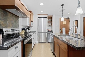 A modern kitchen with stainless steel appliances, a granite countertop, and wooden cabinets.
