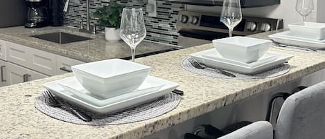 A modern kitchen with white cabinets, a granite countertop, a microwave, and two pendant lights.