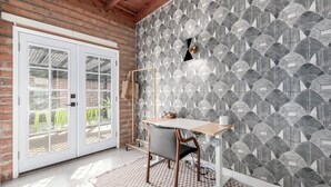 A room with a brick wall, a white door, and a patterned wallpaper. - 3 bedroom Mid Century home with easy access to everything! Pet friendly! (Tucson)