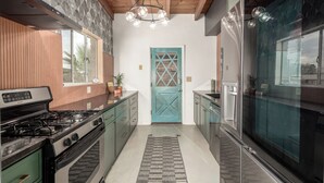 A modern kitchen with a stove, cabinets, and a blue door. - 3 bedroom Mid Century home with easy access to everything! Pet friendly! (Tucson)