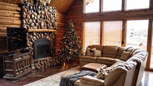 L’intérieur d’un chalet confortable, avec une cheminée en pierre, un canapé en cuir et un sapin de Noël.