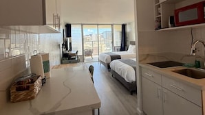 Ein modernes Hotelzimmer mit Küche, Essbereich und einem großen Fenster mit Blick auf die Stadt.