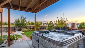 Un jacuzzi bajo una pérgola de madera con un sendero de piedra que conduce a una zona de estar al aire libre.