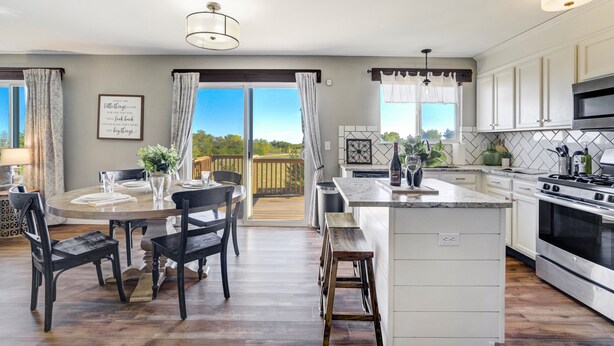 Una cocina moderna con una isla grande, muebles blancos y vistas al exterior.
