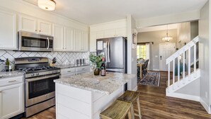 Una cocina moderna con armarios blancos, electrodomésticos de acero inoxidable y una isla de madera.