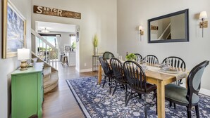 Un comedor con una mesa de madera, sillas negras y un tapete azul con motivos florales.