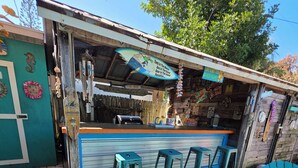 A tiki bar with outdoor seating and a rustic wooden structure. - Port Canaveral/Space X- steps from beach 2-bedroom colorful unit w/ AC-sleeps 8 (Cocoa Beach)