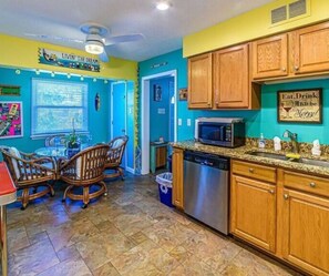 A kitchen with teal walls, wooden cabinets, a stainless steel dishwasher, and a microwave.