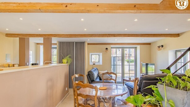 A spacious living area with a wooden ceiling, a dining table with chairs, a sofa, and a TV. - Le Saint-Loup - DRACY SAINT LOUP (DRACY SAINT LOUP)