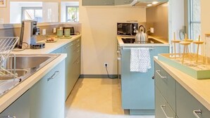 A modern kitchen with light blue cabinets, a stainless steel sink, and a wooden ceiling. - Le Saint-Loup - DRACY SAINT LOUP (DRACY SAINT LOUP)