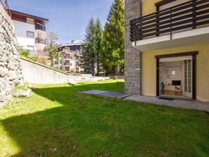 A modern building with a stone facade, a balcony, and a grassy courtyard.