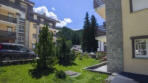 Un immeuble résidentiel doté de nombreux balcons, d’un espace de stationnement et d’un aménagement paysager verdoyant avec des arbres.