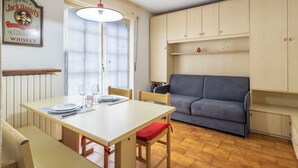 Un coin repas avec une table dressée pour deux personnes, un canapé et un meuble fixé au mur.