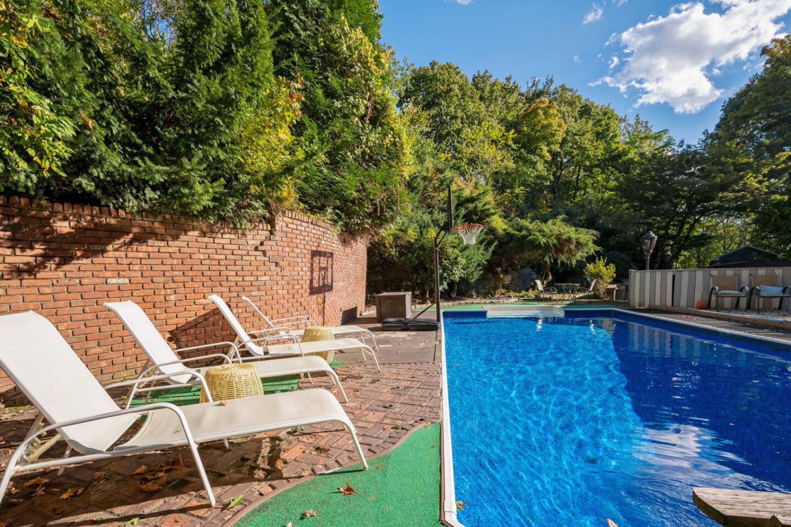 A swimming pool with lounge chairs and a brick wall.