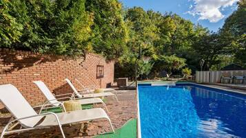 A swimming pool with lounge chairs and a brick wall.