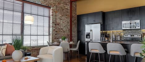 A modern kitchen with dark cabinets, a stainless steel refrigerator, and a built-in oven.