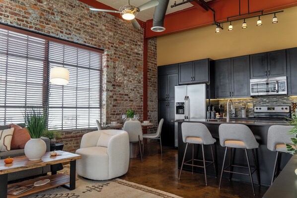 A modern kitchen with dark cabinets, a stainless steel refrigerator, and a built-in oven. - Free Garage + King Bed - Brick Loft in Downtown Roanoke - Walk to everything (Roanoke)