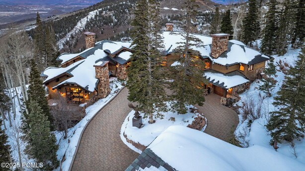 Un albergue cubierto de nieve con varias construcciones, un camino sinuoso y montañas al fondo.