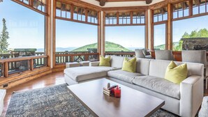 Una habitación amplia con un sofá modular grande, una mesa de centro y vistas a un paisaje montañoso a través de amplias ventanas.