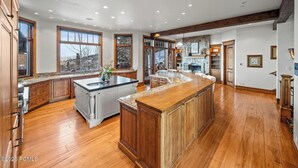 Una cocina amplia con armarios de madera, una isla grande y una chimenea de piedra.