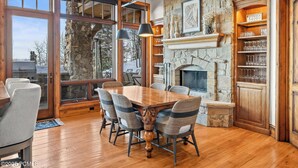 Un comedor con chimenea de piedra, mesa de madera y sillas.