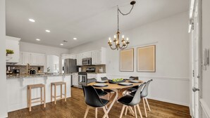 Une cuisine moderne avec des meubles blancs, une table à manger en bois et des chaises noires.