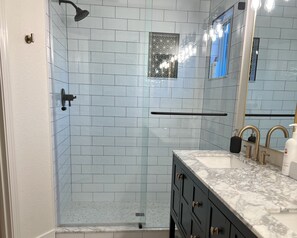 Ein modernes Badezimmer mit einer gläsernen Dusche, einem мраморному Waschbecken und einem großen Spiegel.