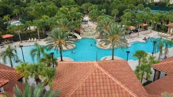 Una gran piscina al aire libre rodeada de palmeras y una estructura con techo de tejas.