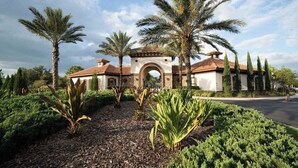 A building with a central archway, surrounded by palm trees and landscaped greenery. - Fabulous 5 BR With Pool Solterra Resort (Davenport)