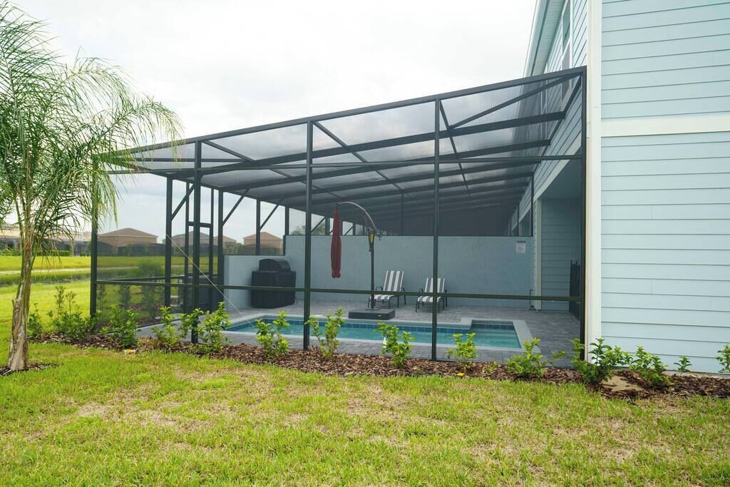 Área externa coberta com piscina, cadeiras e churrasqueira.