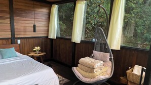 A room with a bed, a hanging chair, and a window with curtains.
