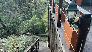 A wooden staircase leading up to a deck area with railings and potted plants.