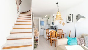 A modern interior with a staircase leading to a kitchen, dining area, and living room.