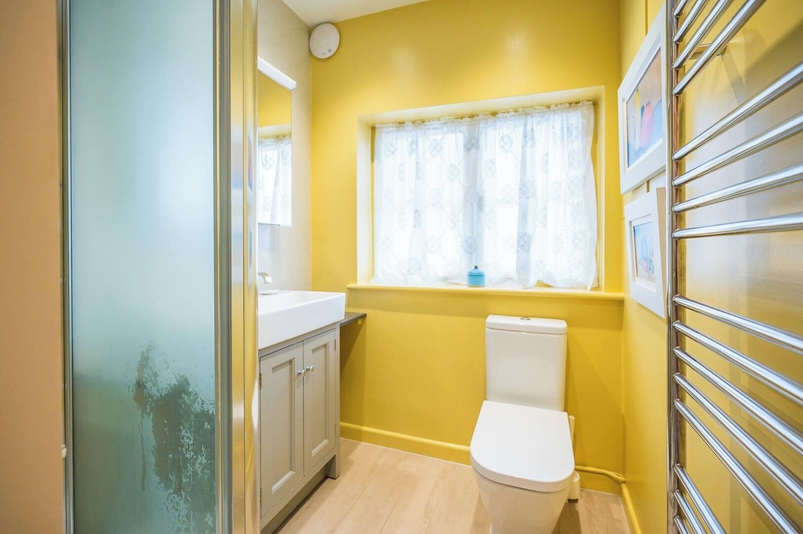 Un baño pequeño con inodoro, lavamanos y ventana con cortinas.