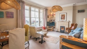 A cozy living room with a fireplace, comfortable seating, and large windows. - 11b Market Cross Place, Aldeburgh (Aldeburgh)