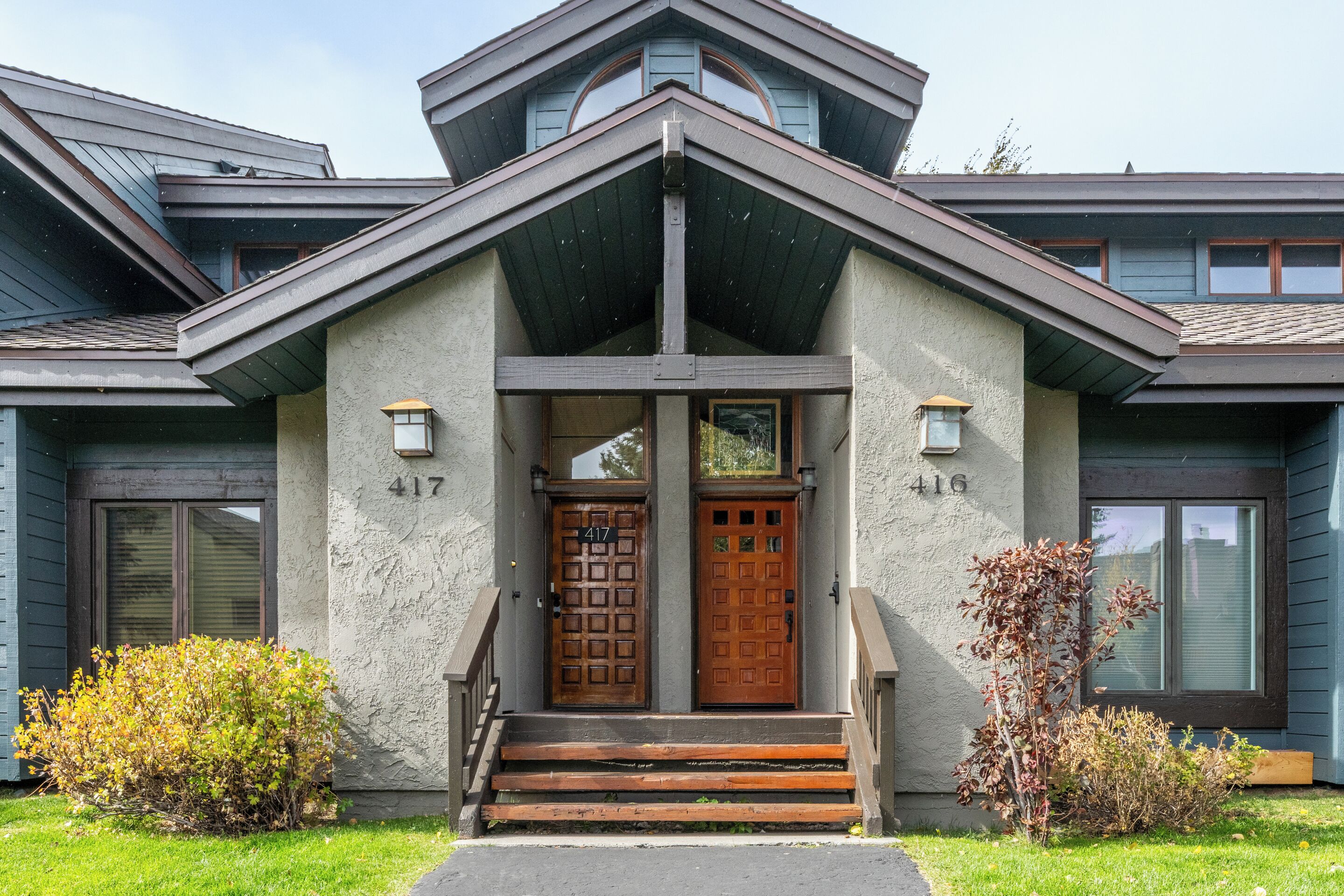 Une maison moderne à la façade symétrique, avec deux portes portant les numéros 417 et 416, et un petit porche avec des marches.