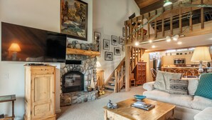 A cozy living room with a fireplace, a wooden coffee table, a sofa, and a staircase leading to an upper level. - 3 Bedrooms + Loft townhome in Snowcreek Phase 3,  Private Pool Table Sleeps 6 Guests, Dog Friendly (Mammoth Lakes)