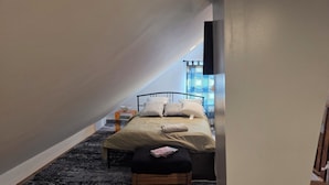 Une chambre à coucher avec un lit, une table de chevet et une fenêtre avec des rideaux.