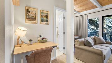 Une pièce comprenant un bureau, une chaise et un canapé. Deux tableaux encadrés sont accrochés au mur.