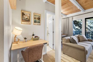 Une pièce comprenant un bureau, une chaise et un canapé. Deux tableaux encadrés sont accrochés au mur.