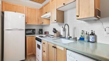 Una cocina con armarios de madera, un refrigerador blanco, una estufa, un lavamanos y un lavavajillas.