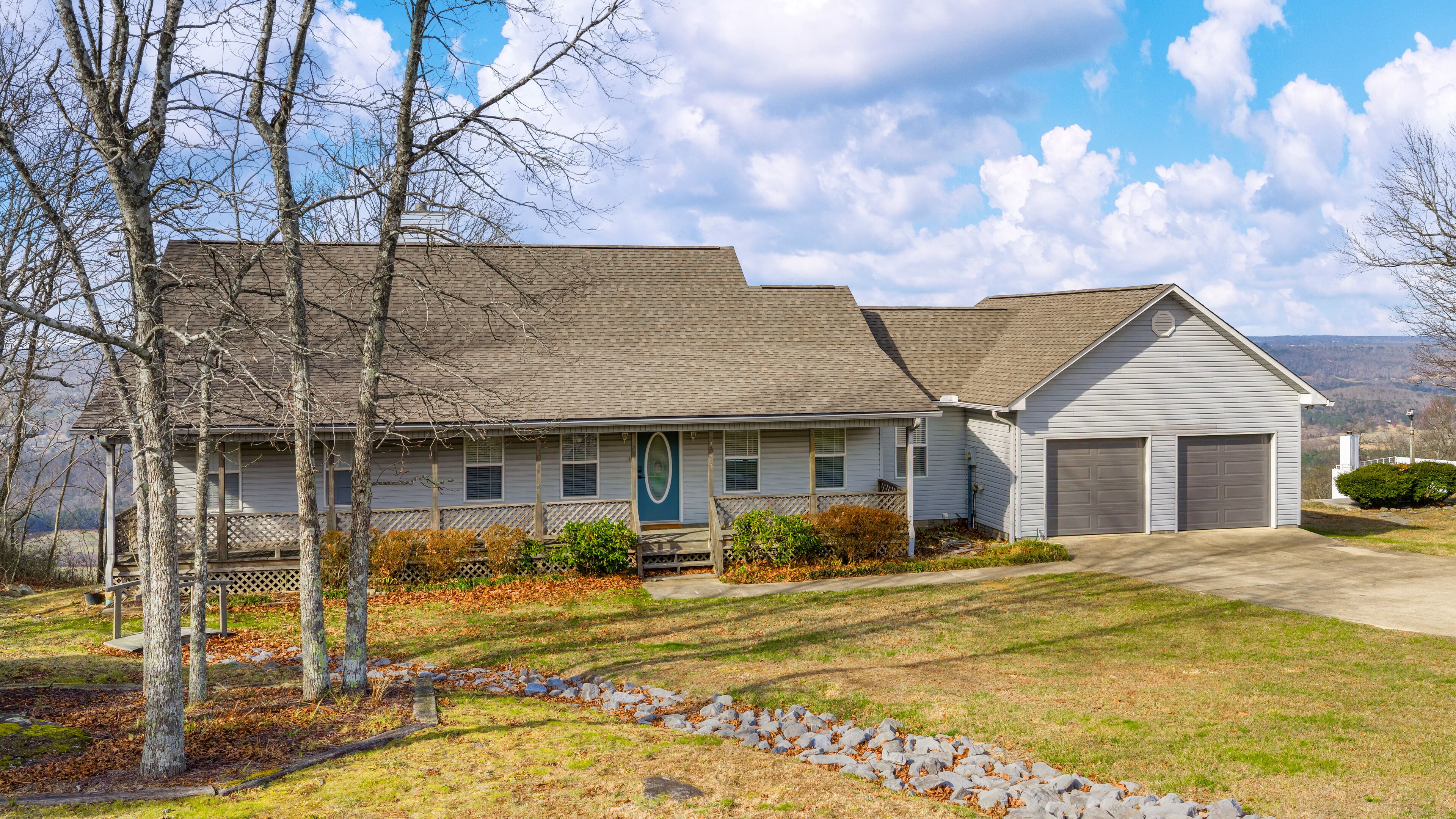 A two-story house with a garage, a front porch, and a stone pathway leading to the entrance.