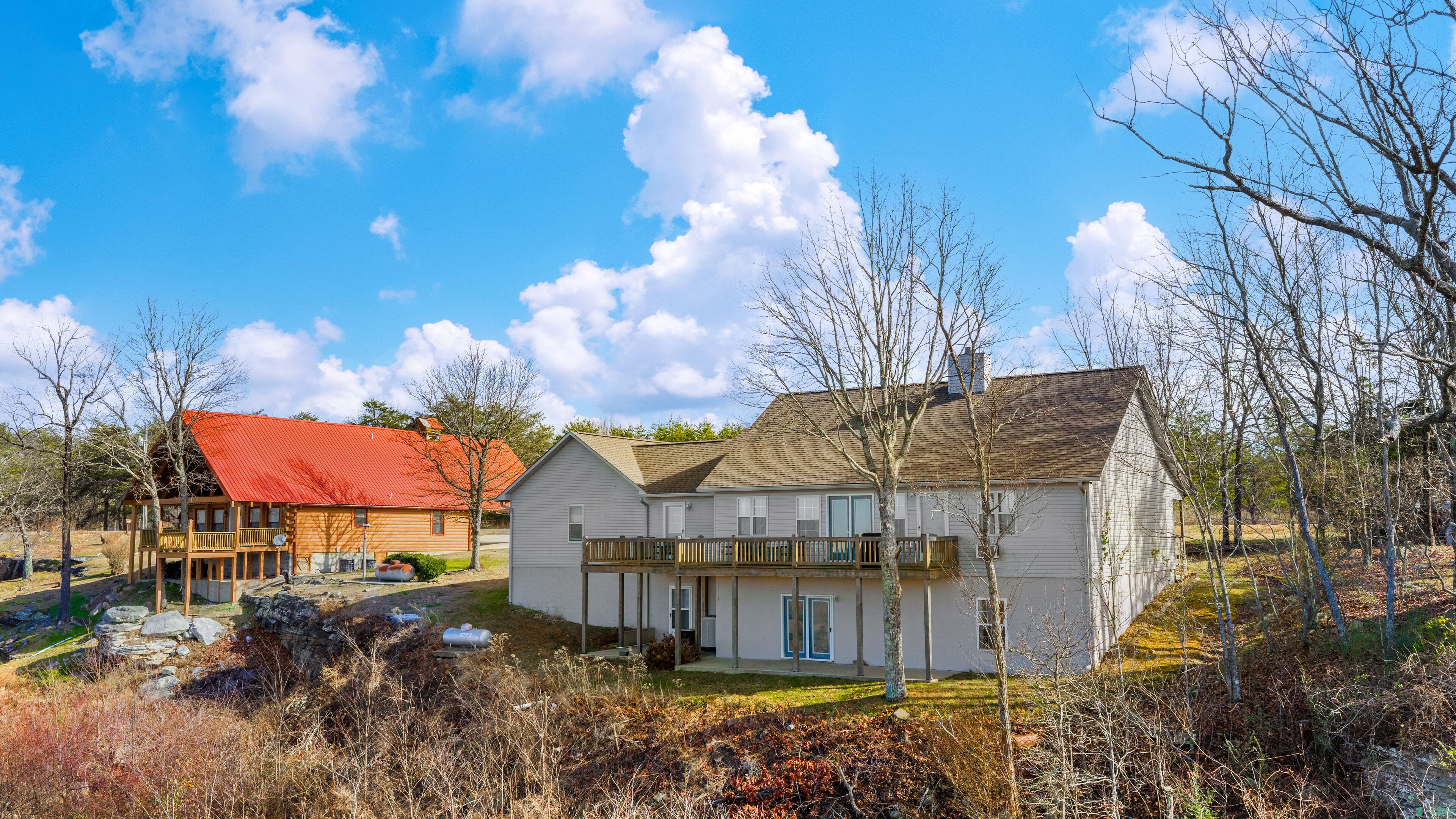 Ein zweistöckiges Haus mit rotem Dach und weißer Fassade, umgeben von Bäumen und einem grünen Rasen.