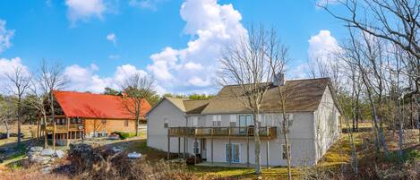 Ein zweistöckiges Haus mit rotem Dach und weißer Fassade, umgeben von Bäumen und einem grünen Rasen.