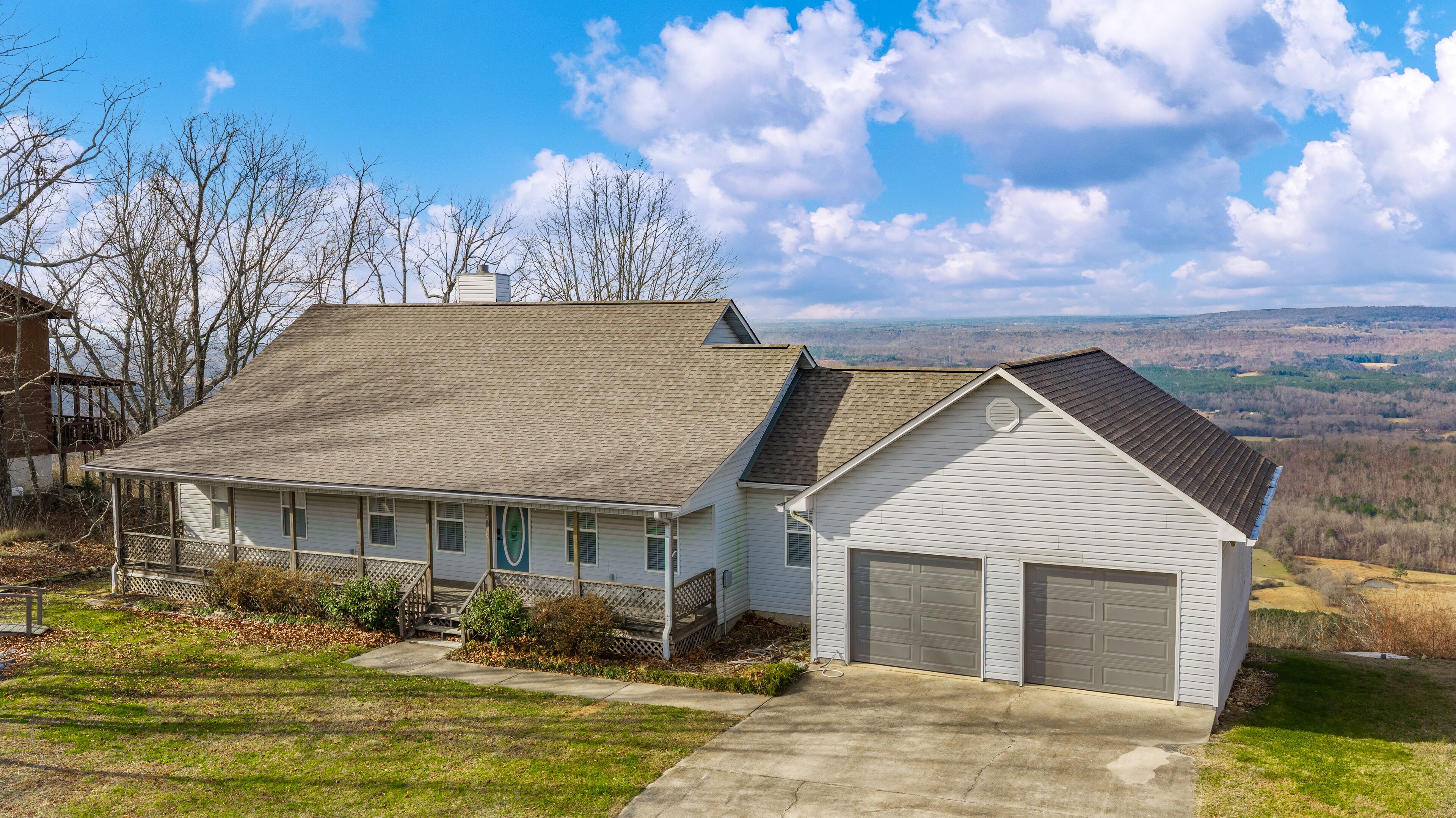 A two-story house with a garage, a covered porch, and a view of the surrounding landscape.