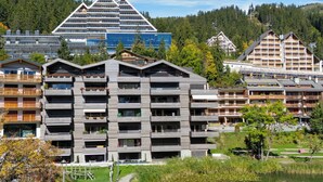 A multi-story hotel with a modern design, featuring balconies with plants and a view of a lake. - Central Parc 2 by Interhome (Crans-Montana)