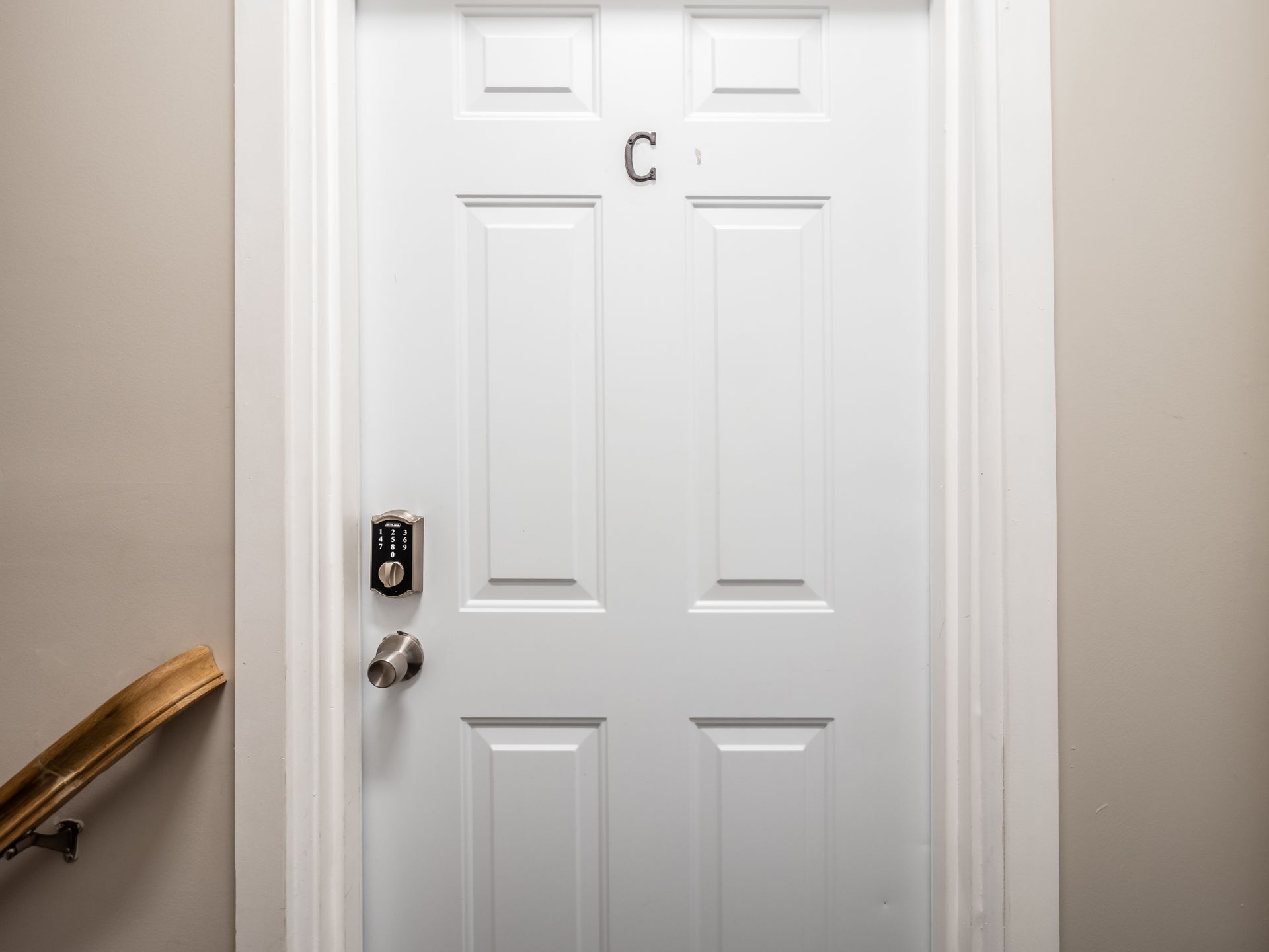 A white door with a keypad lock and a letter 'C' above it.